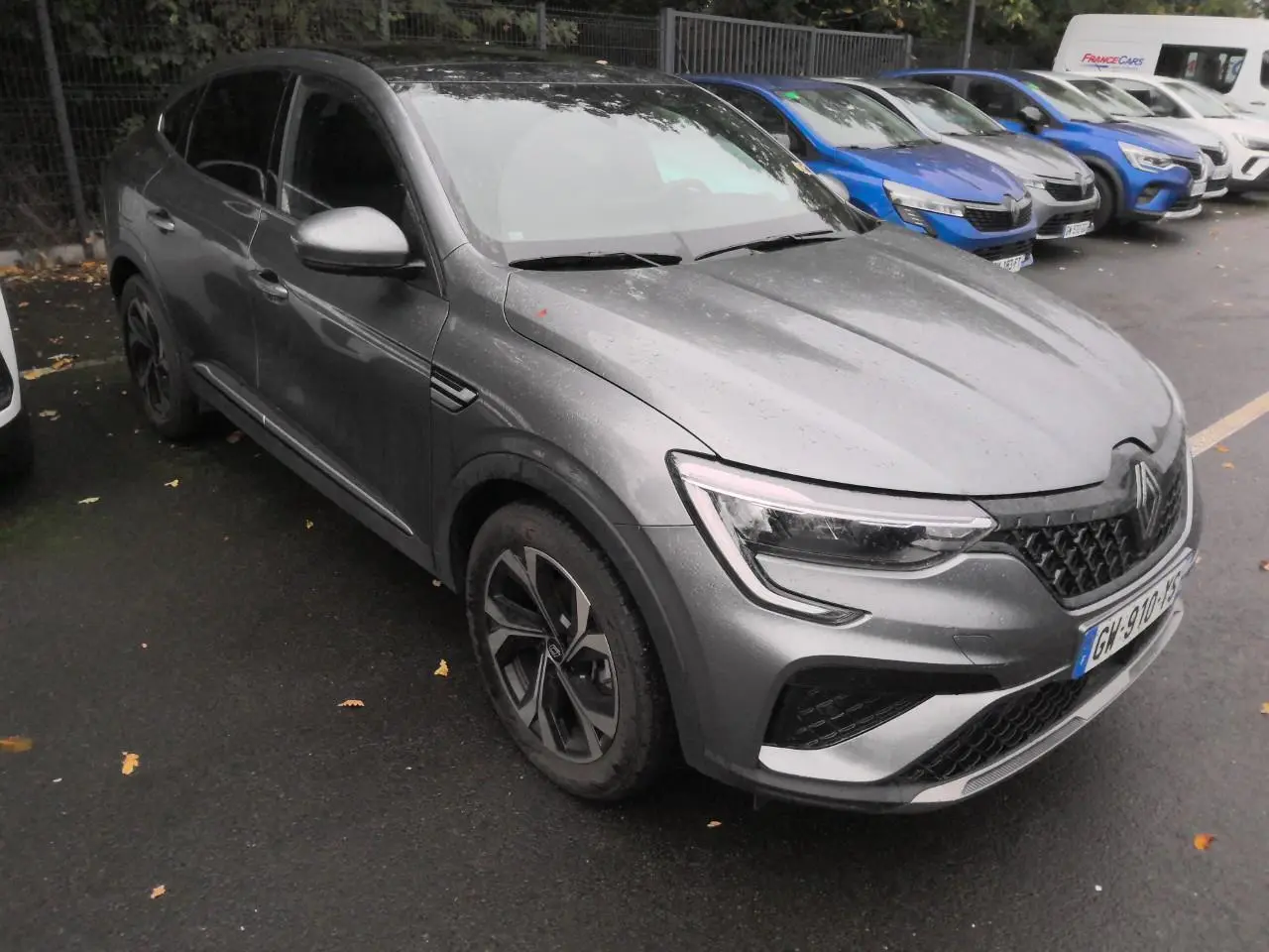 Renault Arkana gris métal foncé vu en 3/4 avant droit, avec jantes alliage et toit ouvrant électrique visible.