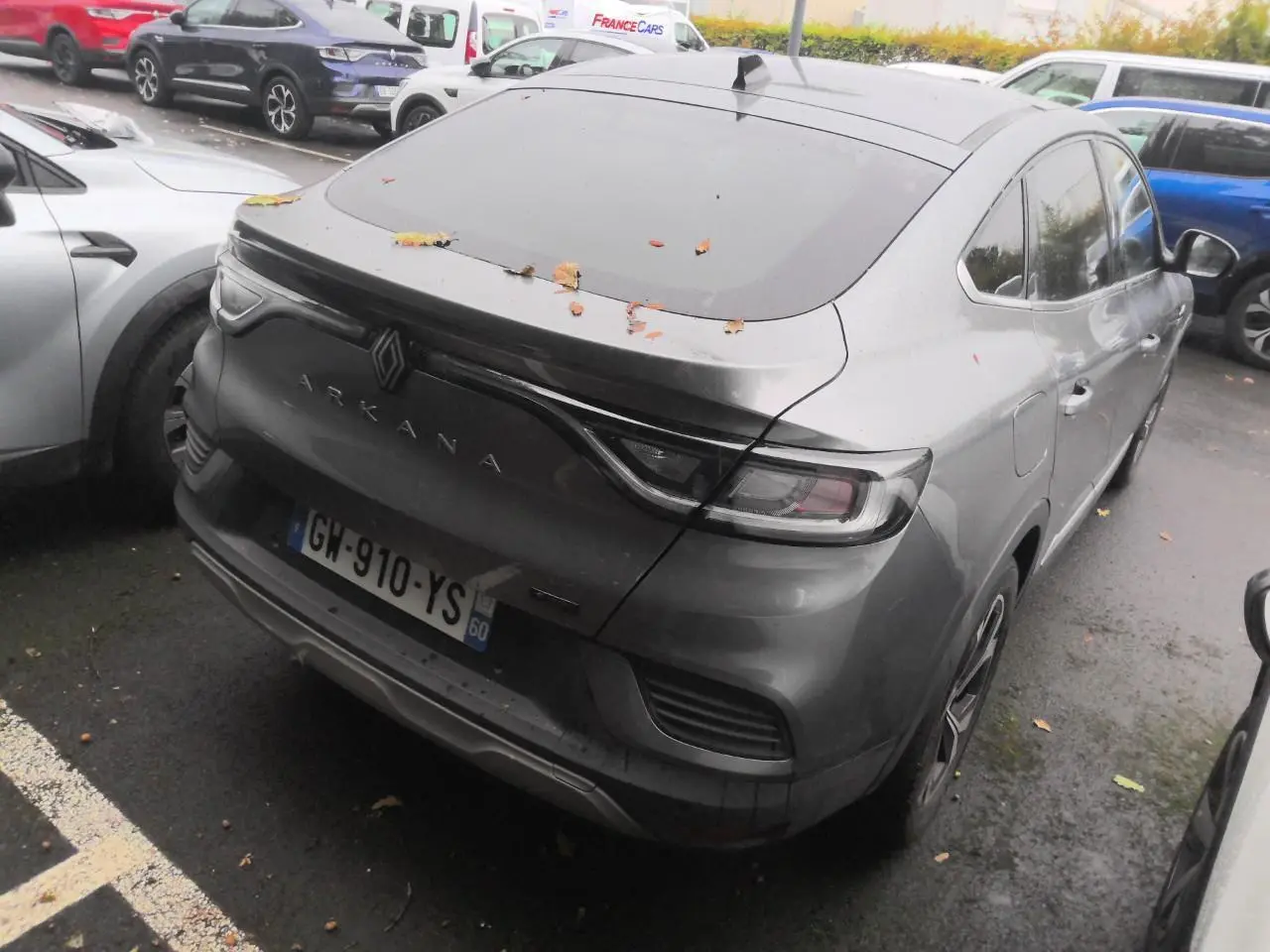 Vue 3/4 arrière droit du Renault Arkana gris métal foncé avec toit ouvrant et feux arrière LED reliés par un bandeau noir.