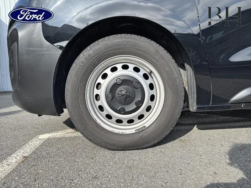 Gros plan sur la roue avant gauche noire Perla Nera du Peugeot Expert Fourgon avec jante acier et logo lion central.