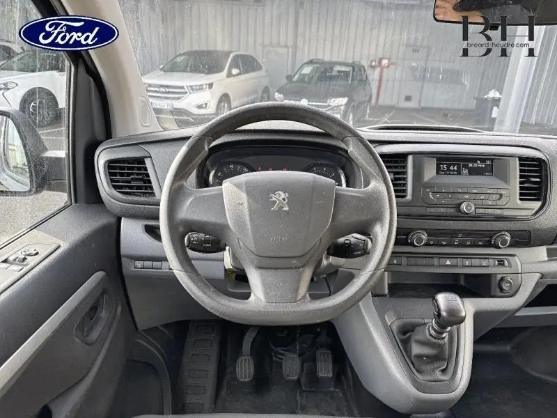 Vue intérieure frontale du tableau de bord noir du Peugeot Expert Fourgon 2022 avec volant, commandes et levier de vitesse manuel.