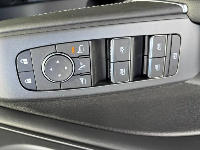 Gros plan sur les commandes de réglage des rétroviseurs et des vitres côté conducteur du Nissan Qashqai e-POWER gris Argile.