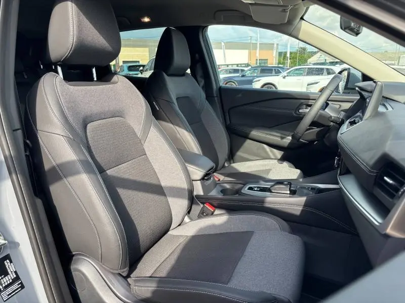 Vue intérieure côté conducteur du Nissan Qashqai e-POWER 2024, sièges mixte tissu et TEP noirs avec surpiqûres contrastantes.
