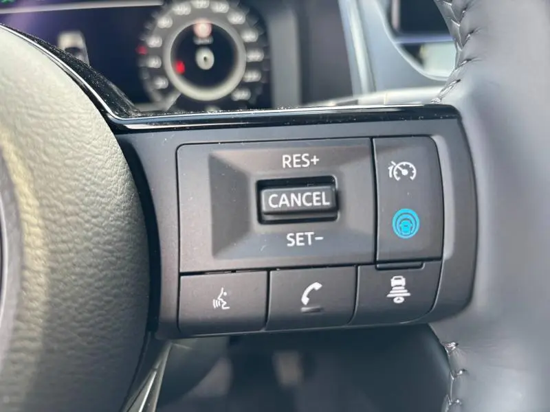 Gros plan sur les commandes de régulateur de vitesse au volant cuir du Nissan Qashqai e-POWER 2024.