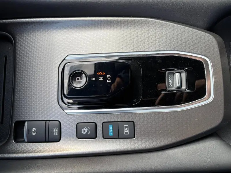 Vue plongeante sur la console centrale du Nissan Qashqai e-POWER 2024, avec sélecteur de boîte auto et boutons EV et parking.