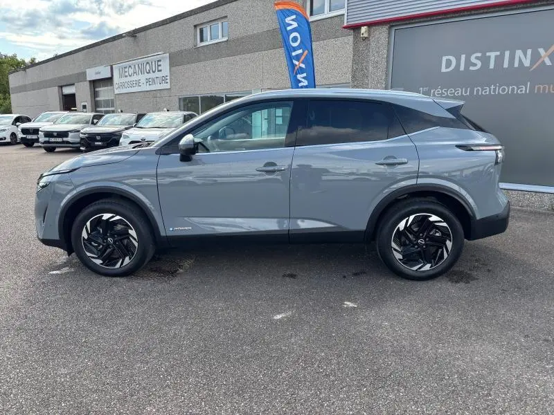 Vue de profil côté gauche d'un Nissan Qashqai e-POWER 2024 en gris Argile avec jantes alliage noires et toit noir contrasté.
