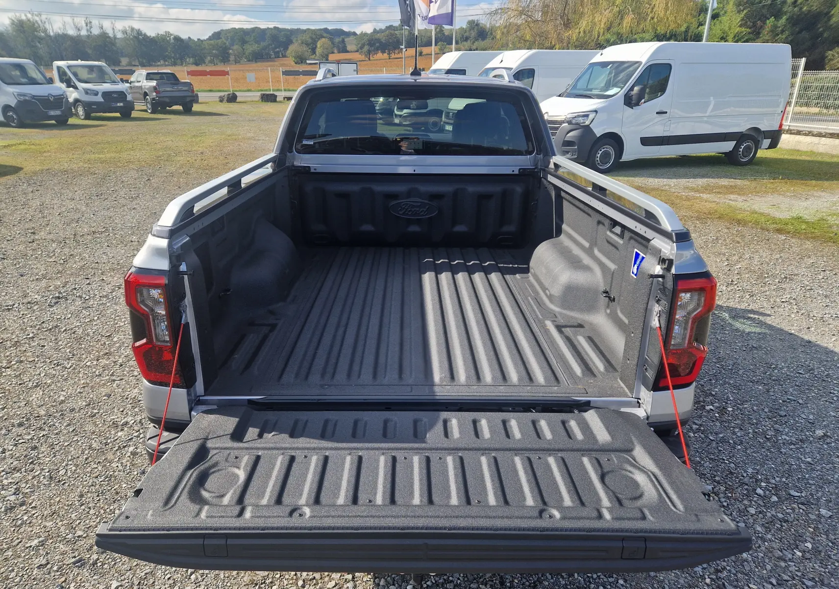 Vue arrière d'un Ford Ranger Super Cabine gris Iconic avec benne ouverte et protection en plastique visible.
