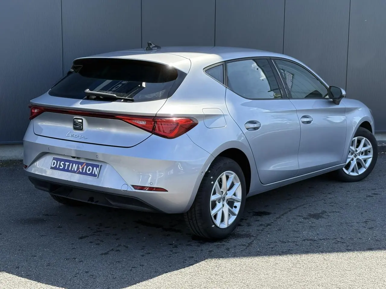 Vue 3/4 arrière droite d'une SEAT Leon 2024 gris argent avec vitres arrière surteintées et jantes alliage 16 pouces.
