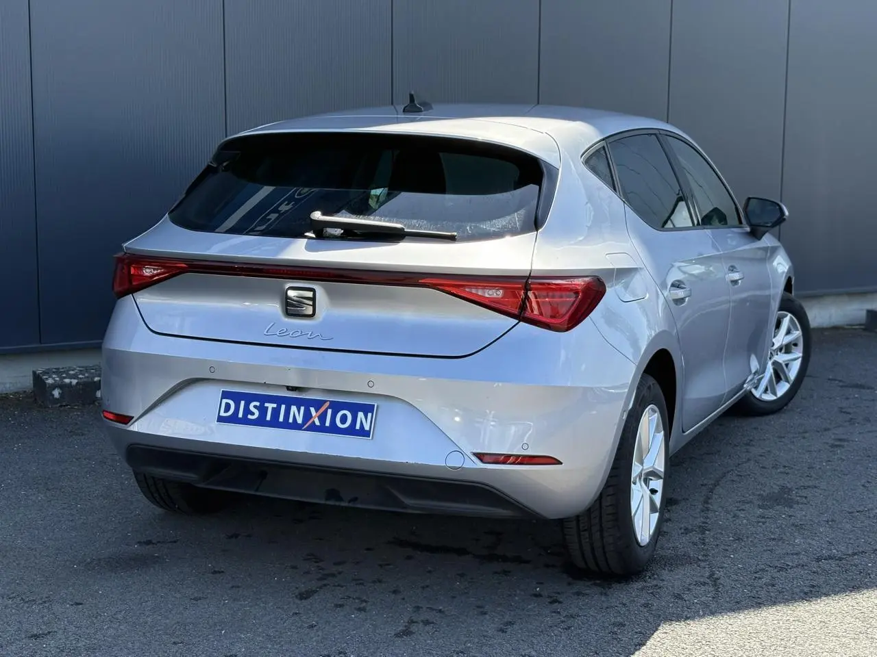 Vue 3/4 arrière droite d'une SEAT Leon gris argent avec vitres arrière surteintées et feux arrière LED.