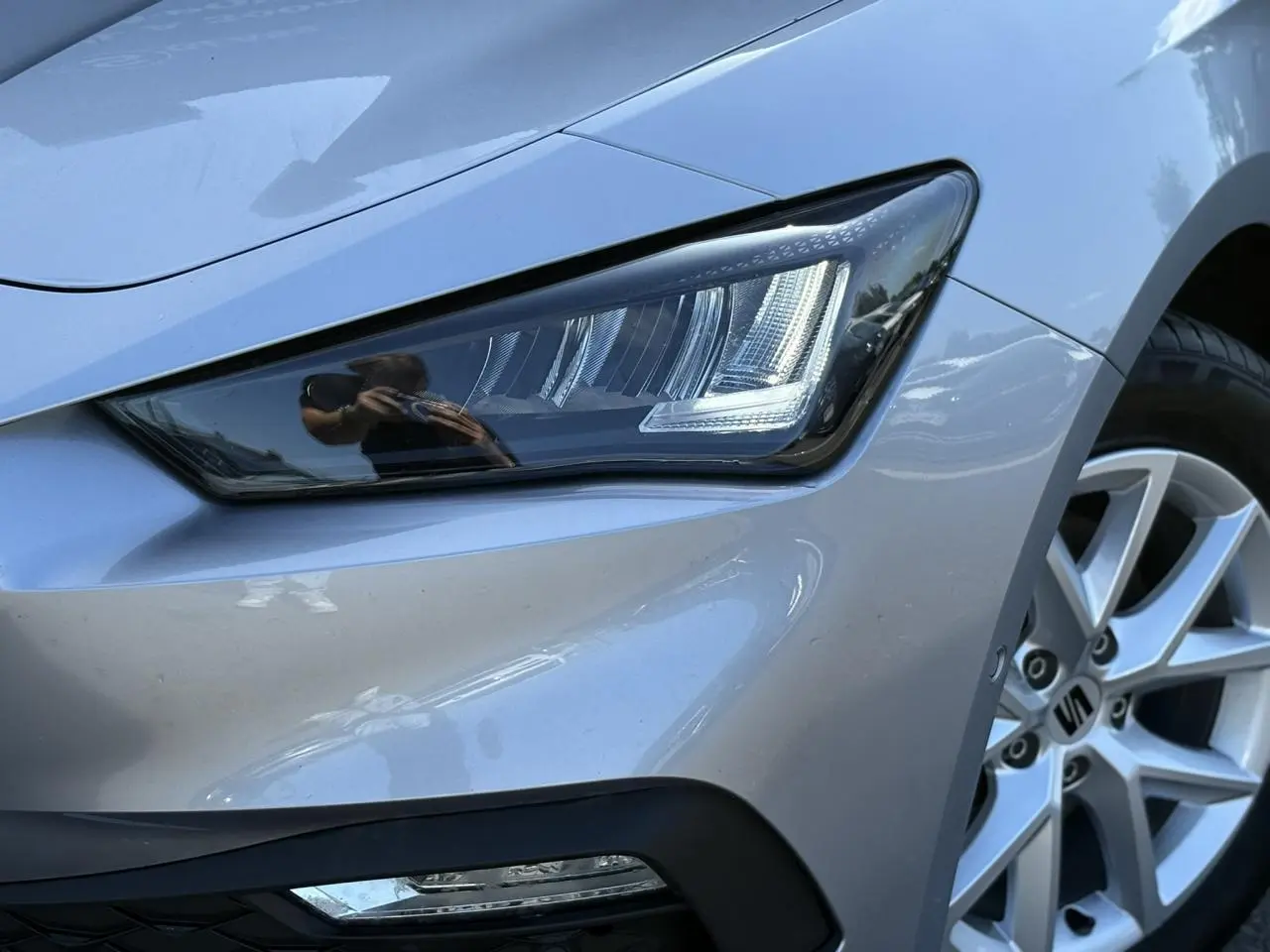 Gros plan sur le phare avant droit et la jante alliage gris argent d'une SEAT LEON 2.0 TDI 2024.