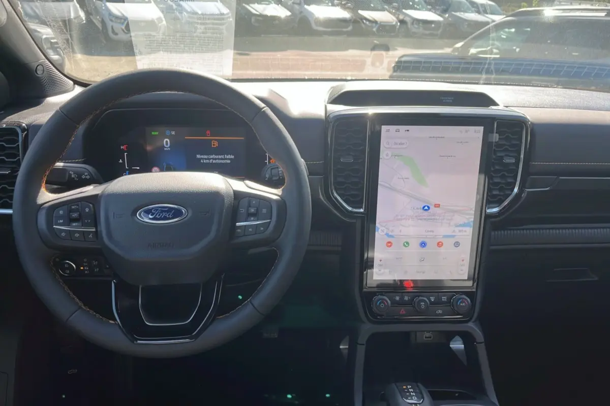 Vue intérieure du tableau de bord du Ford Ranger 2.3 PHEV 281 Wildtrak Plus 2025 avec écran tactile vertical et volant multifonction.