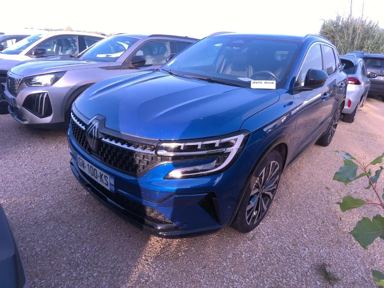 Renault Austral bleu métal foncé en 3/4 avant droit, avec calandre damier ice black et jantes alliage 20 pouces.