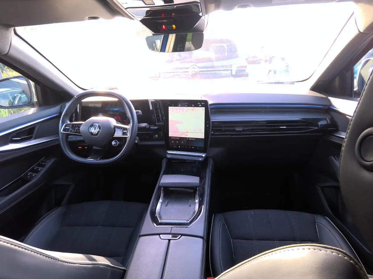 Intérieur du Renault Austral 2024 vu de l'arrière, tableau de bord moderne avec écran tactile vertical et volant compact noir.