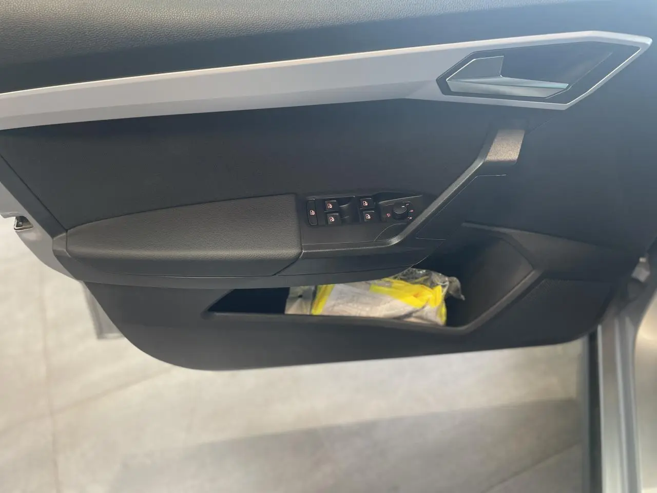 Vue rapprochée de la porte avant gauche de la SEAT ARONA 2024, avec commandes de vitres et rangements noirs.