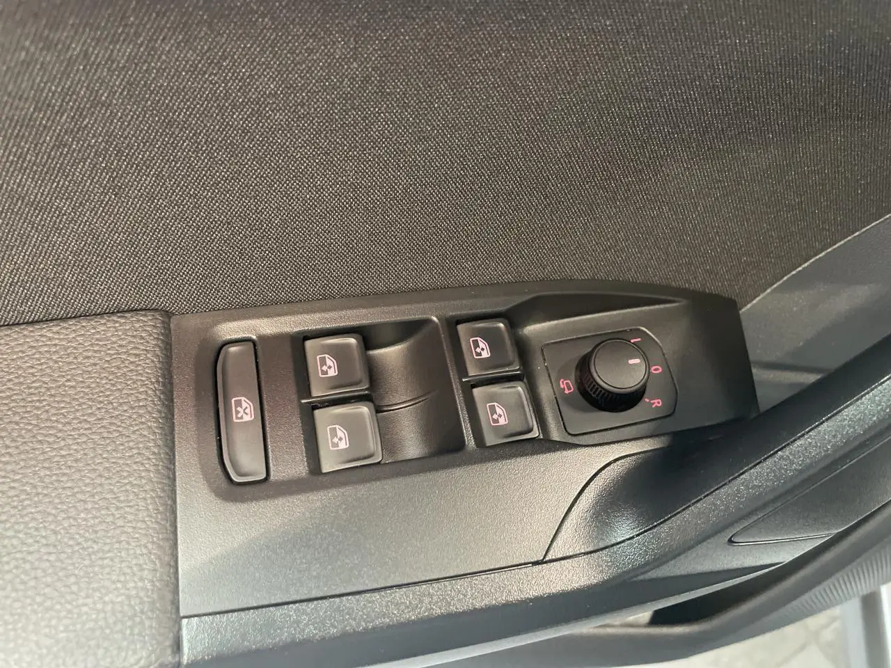 Vue rapprochée des commandes des vitres électriques et des rétroviseurs côté conducteur d'une SEAT Arona rouge GRS 2024.