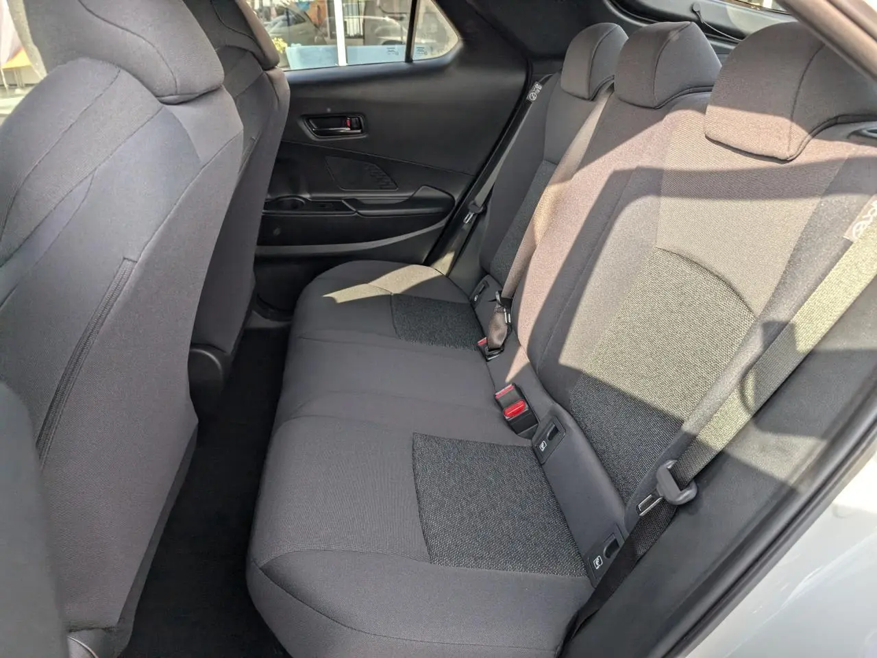 Vue intérieure côté droit des sièges arrière en tissu gris foncé du Toyota C-HR 1.8 Hybrid blanc 2024.