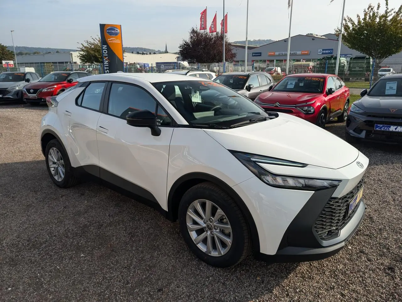 Toyota C-HR blanc en 3/4 avant droit, avec calandre noire et jantes alliage 17 pouces visibles.