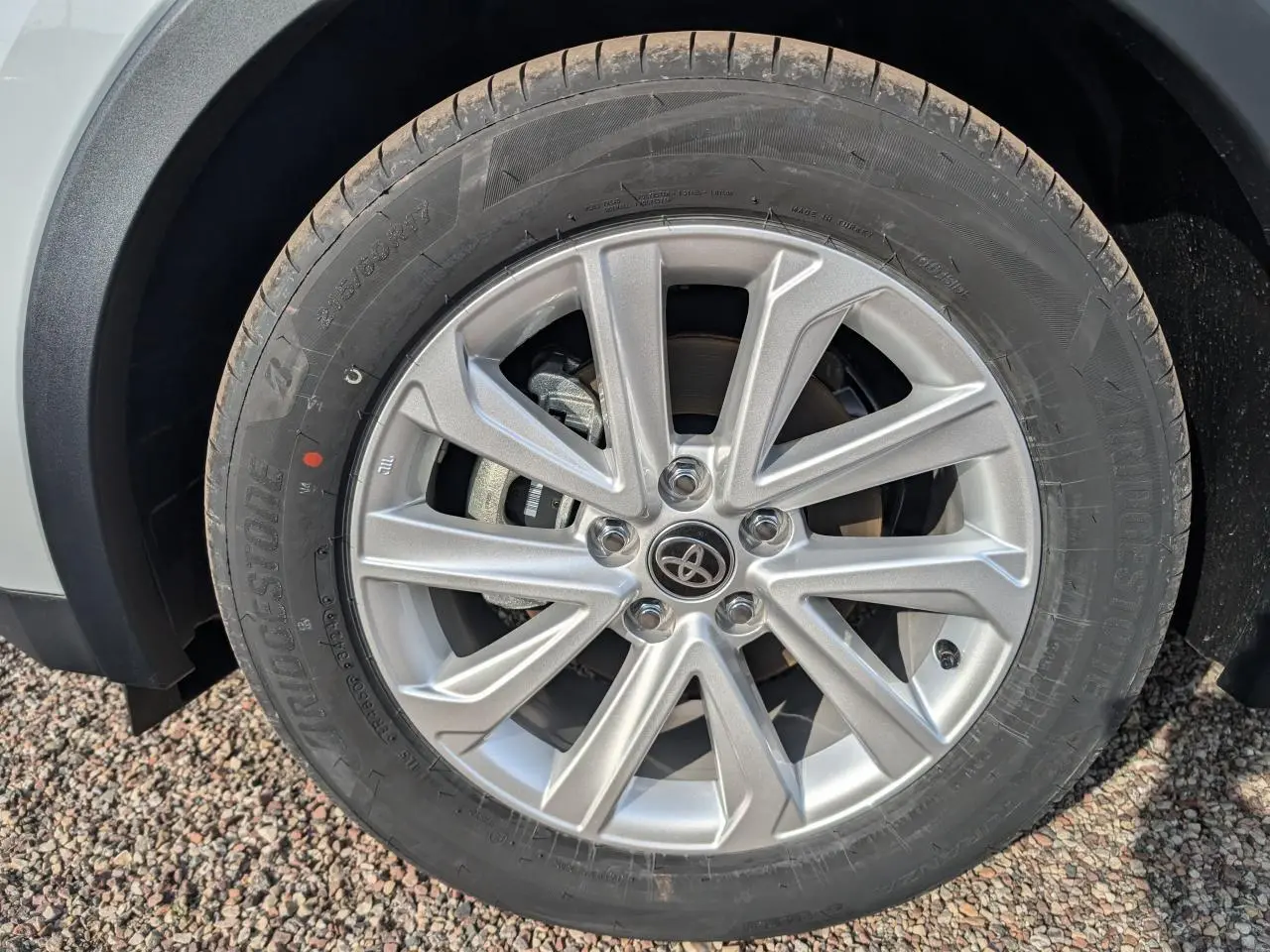 Gros plan sur la jante alliage 17 pouces argentée avec logo Toyota au centre, montée sur pneu Bridgestone.