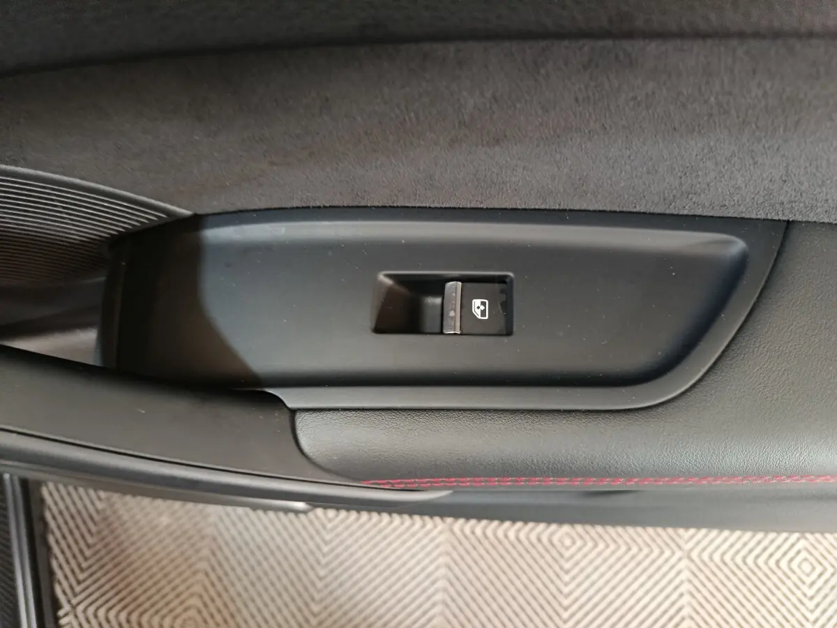 Bouton de commande de lève-vitre sur la porte intérieure noire avec surpiqûres rouges d'un Audi Q5 gris clair hybride rechargeable 2023.