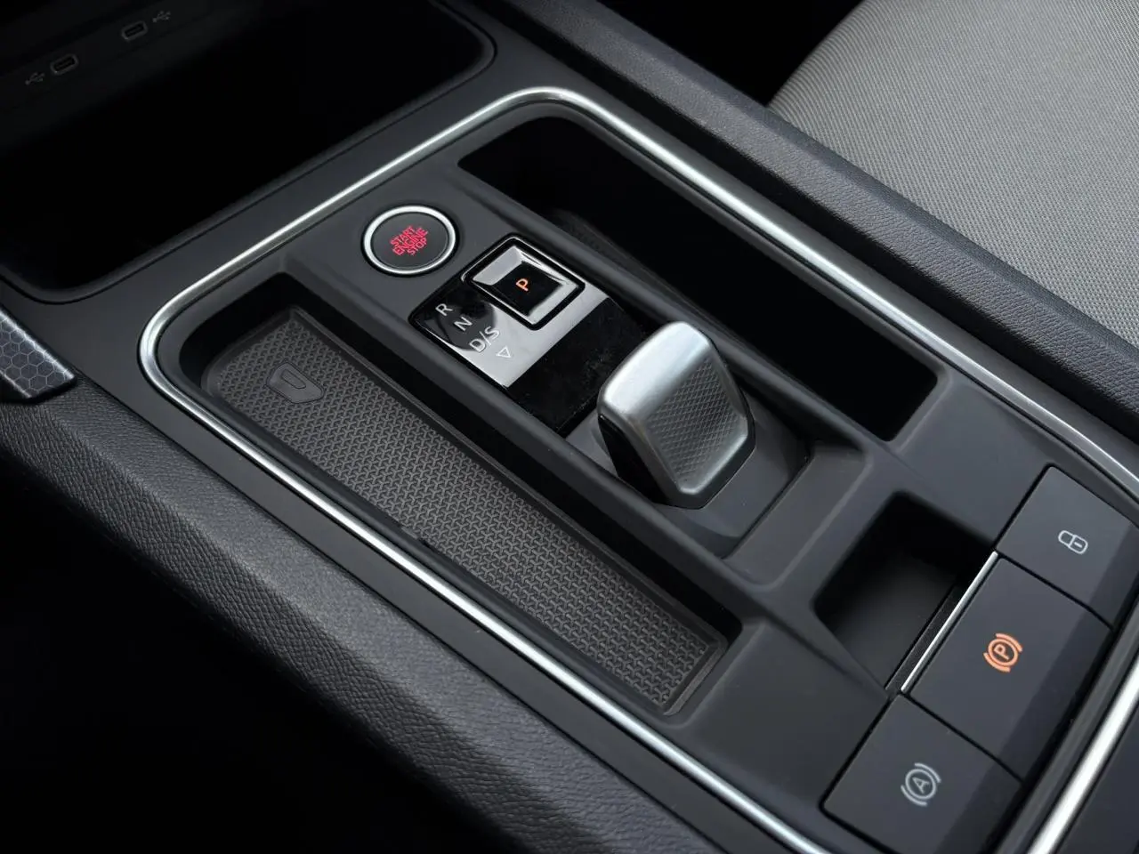 Gros plan sur la console centrale noire de la SEAT LEON 2.0 TDI 150 DSG Style avec levier de vitesse électronique et bouton Start/Stop rouge.