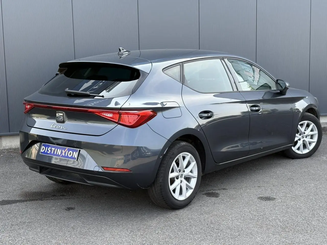 Vue 3/4 arrière droite d'une SEAT Leon gris magnétique avec feux arrière LED et jantes alliage 16 pouces.