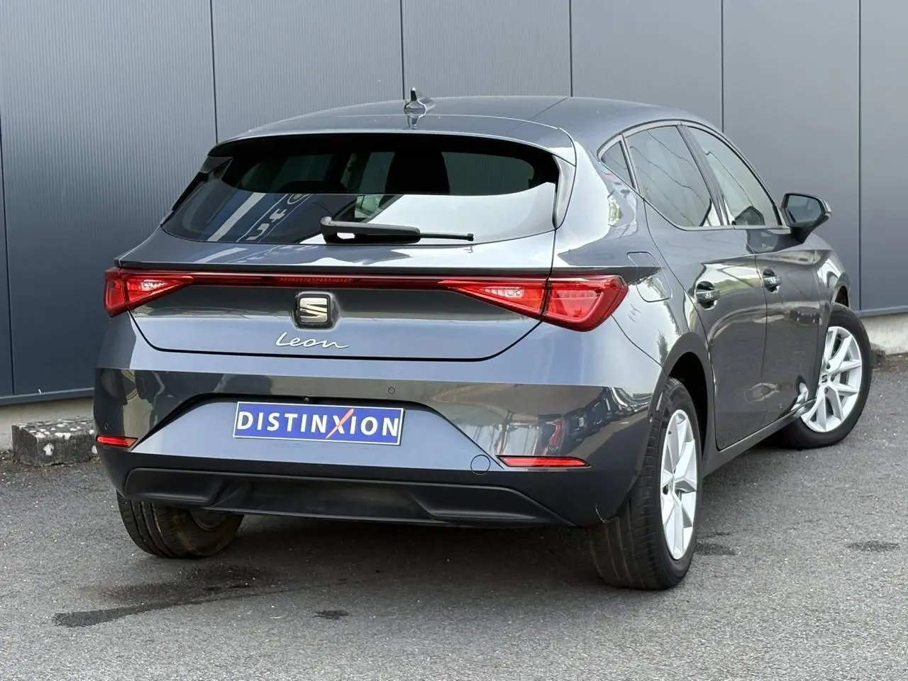 Vue 3/4 arrière droite d'une SEAT Leon 2024 gris magnétique avec feux arrière LED et vitres surteintées.