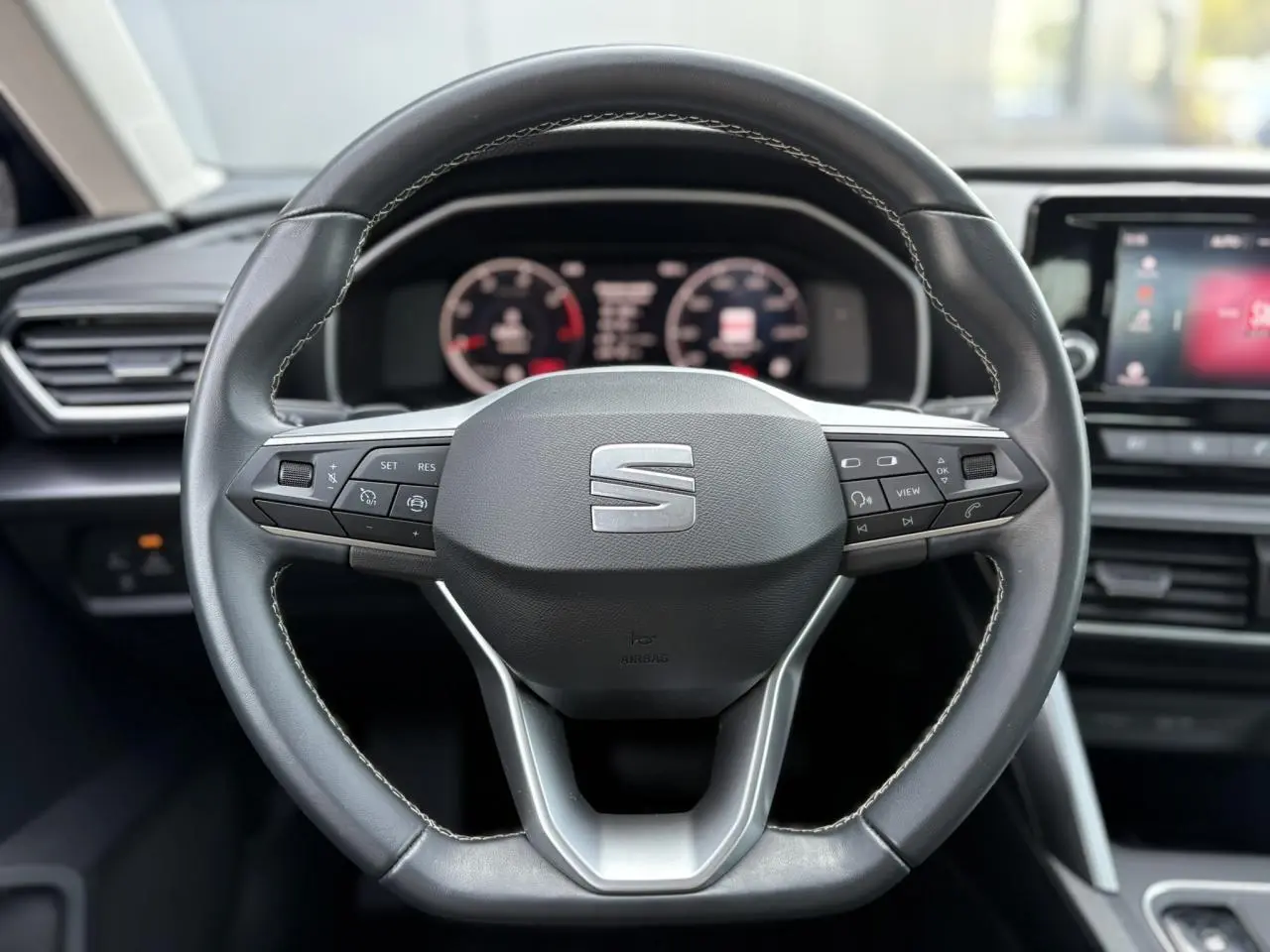 Volant cuir multifonction de la SEAT LEON 2024 avec commandes intégrées, tableau de bord digital et écran tactile visible.