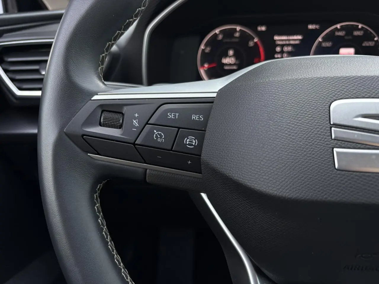 Gros plan sur le volant cuir multifonction de la SEAT LEON 2024 avec commandes de régulateur et assistance au pilotage.