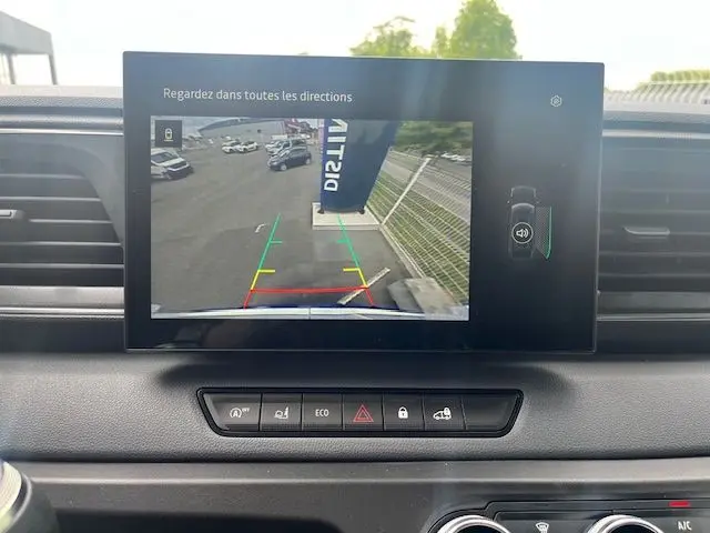 Écran central montrant la caméra de recul du Nissan Interstar blanc, avec lignes de guidage colorées et vue arrière du parking.