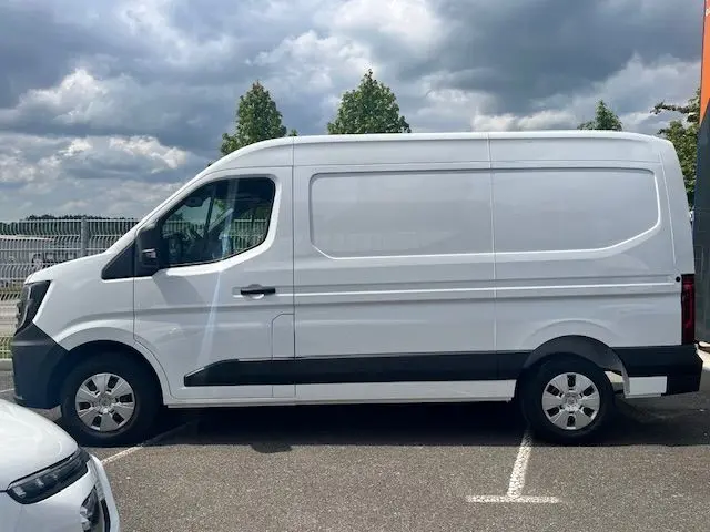 Vue latérale gauche d'un fourgon blanc Nissan Interstar 2025 avec bande noire basse et jantes argentées.