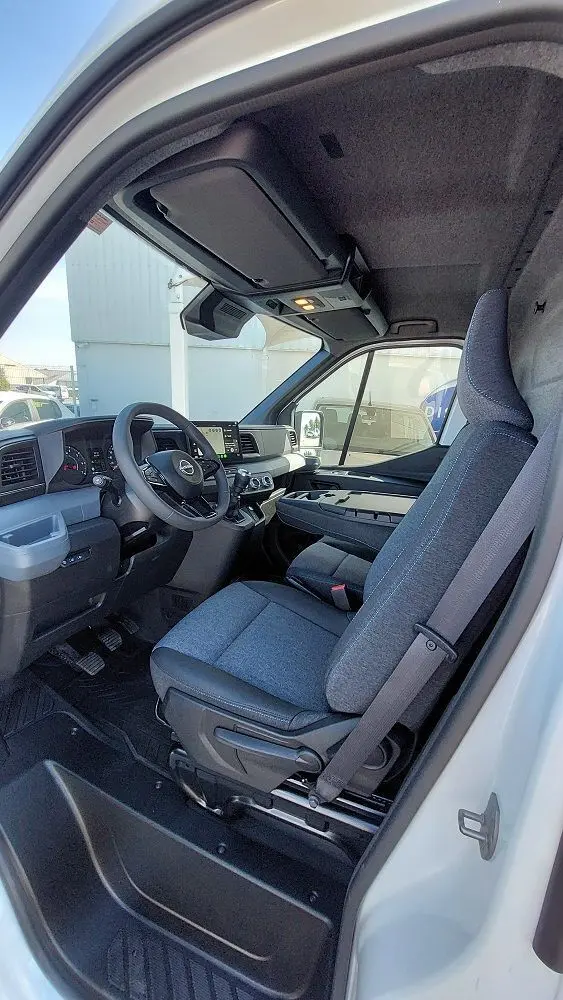 Vue intérieure côté conducteur du Nissan Interstar Fourgon blanc 2025, avec siège gris et tableau de bord moderne.