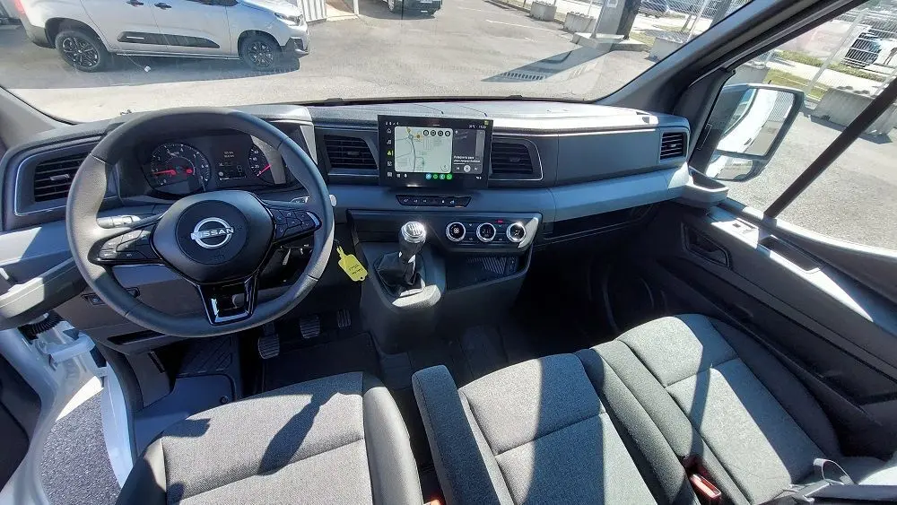 Vue intérieure avant du Nissan Interstar Fourgon blanc 2025, tableau de bord moderne avec écran tactile et volant multifonction.