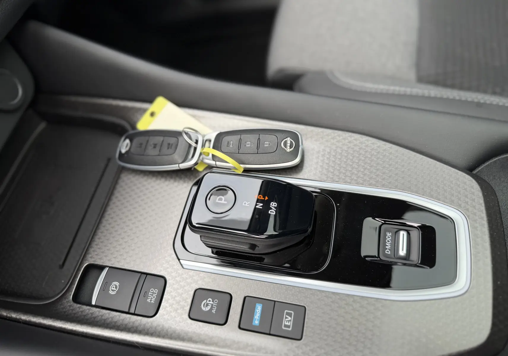 Gros plan sur la console centrale grise du Nissan Qashqai 2025 avec boîte auto et clés posées à côté.