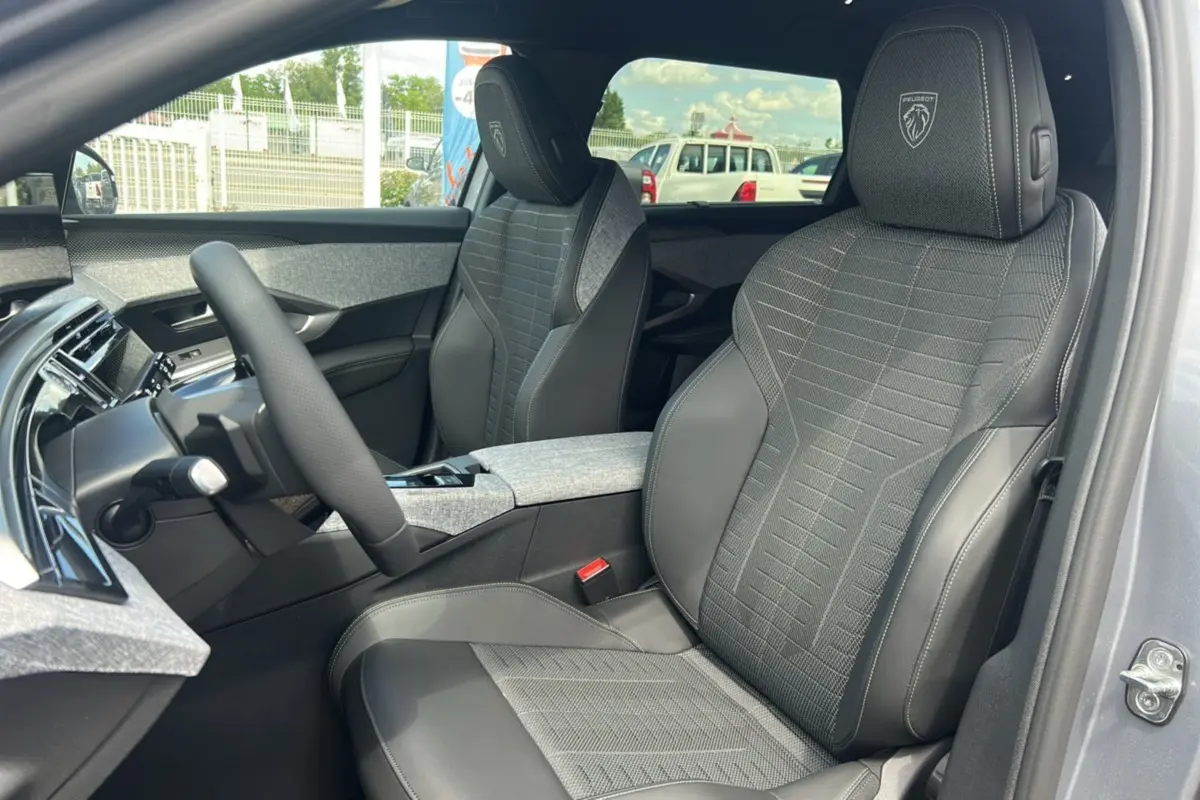 Vue intérieure du PEUGEOT 5008 HYBRID 145 GT 7 places, sièges avant gris avec logo Peugeot brodé sur les appuie-têtes.