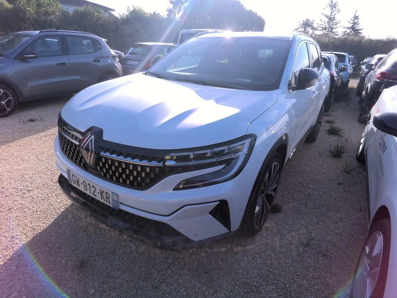 Renault Austral blanc nacré vu de face droite, calandre damier ice black et jantes alliage 20 pouces visibles.
