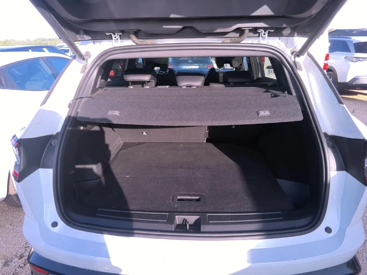 Coffre ouvert vu de l'arrière d'un Renault Austral blanc nacré, montrant l'espace de chargement vide et la plage arrière.