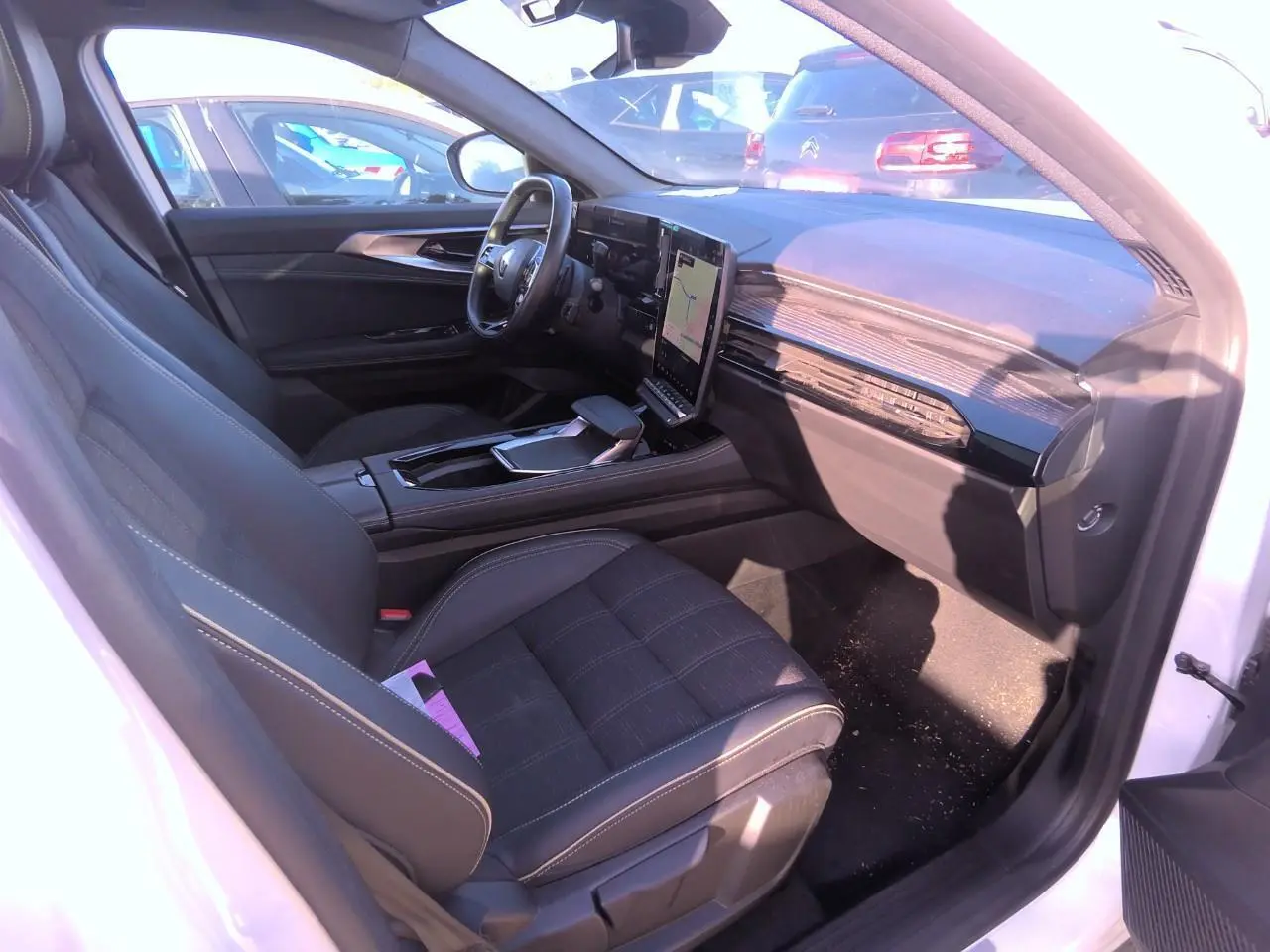 Intérieur côté conducteur du Renault Austral blanc nacré 2024, avec tableau de bord moderne et écran tactile vertical.