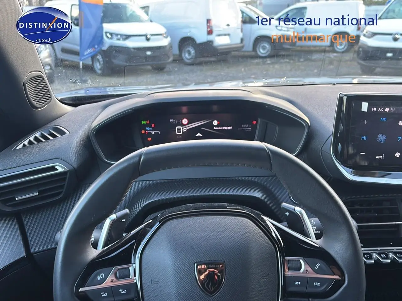 Vue intérieure centrée sur le volant cuir noir et le tableau de bord numérique du Peugeot 2008 1.2 hybrid 145 allure.