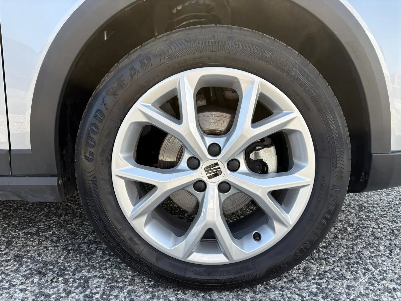 Gros plan sur la jante alliage 16 pouces argentée avec logo SEAT, partie avant gauche du SEAT Arona rouge GRS.