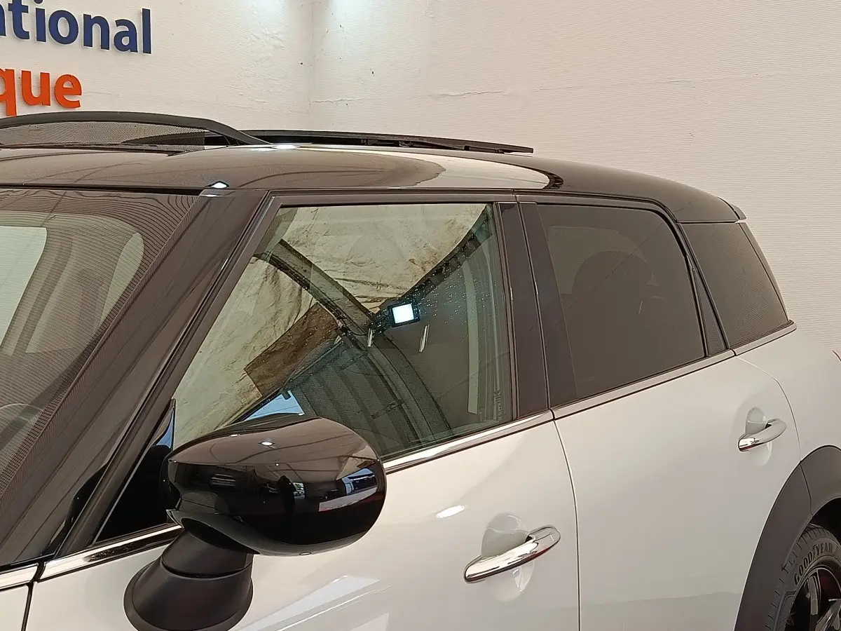 Vue latérale droite d'un MINI Countryman blanc avec toit noir et rétroviseur noir brillant.