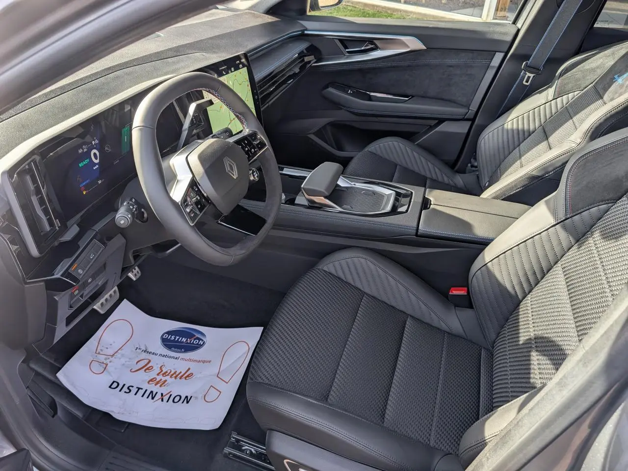 Vue intérieure côté conducteur du Renault Austral gris métallisé, avec sellerie mixte Alcantara et volant textile spécifique.