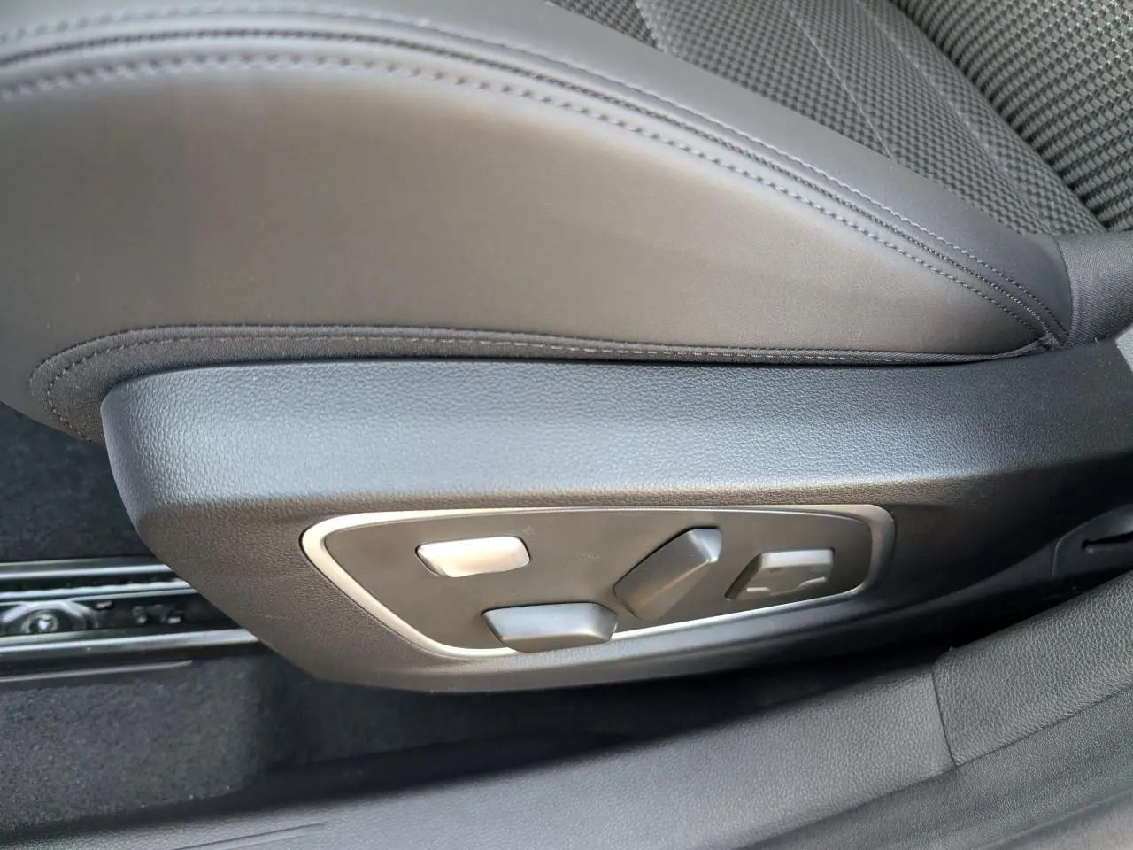 Gros plan sur les commandes électriques du siège conducteur en sellerie mixte tissu carbone Alcantara gris.