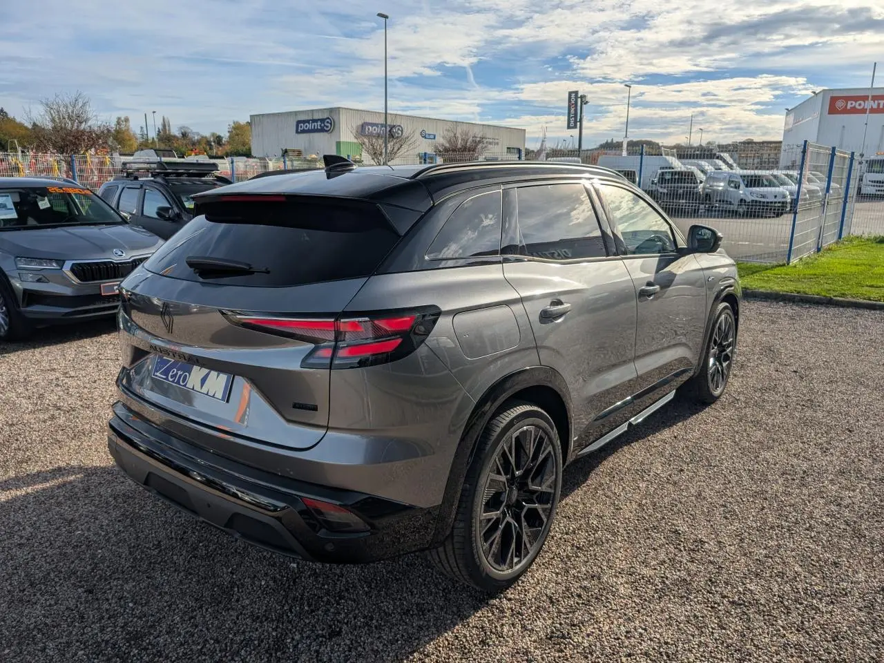 Vue 3/4 arrière droite du Renault Austral gris métallisé avec toit noir étoilé et jantes alliage noires.
