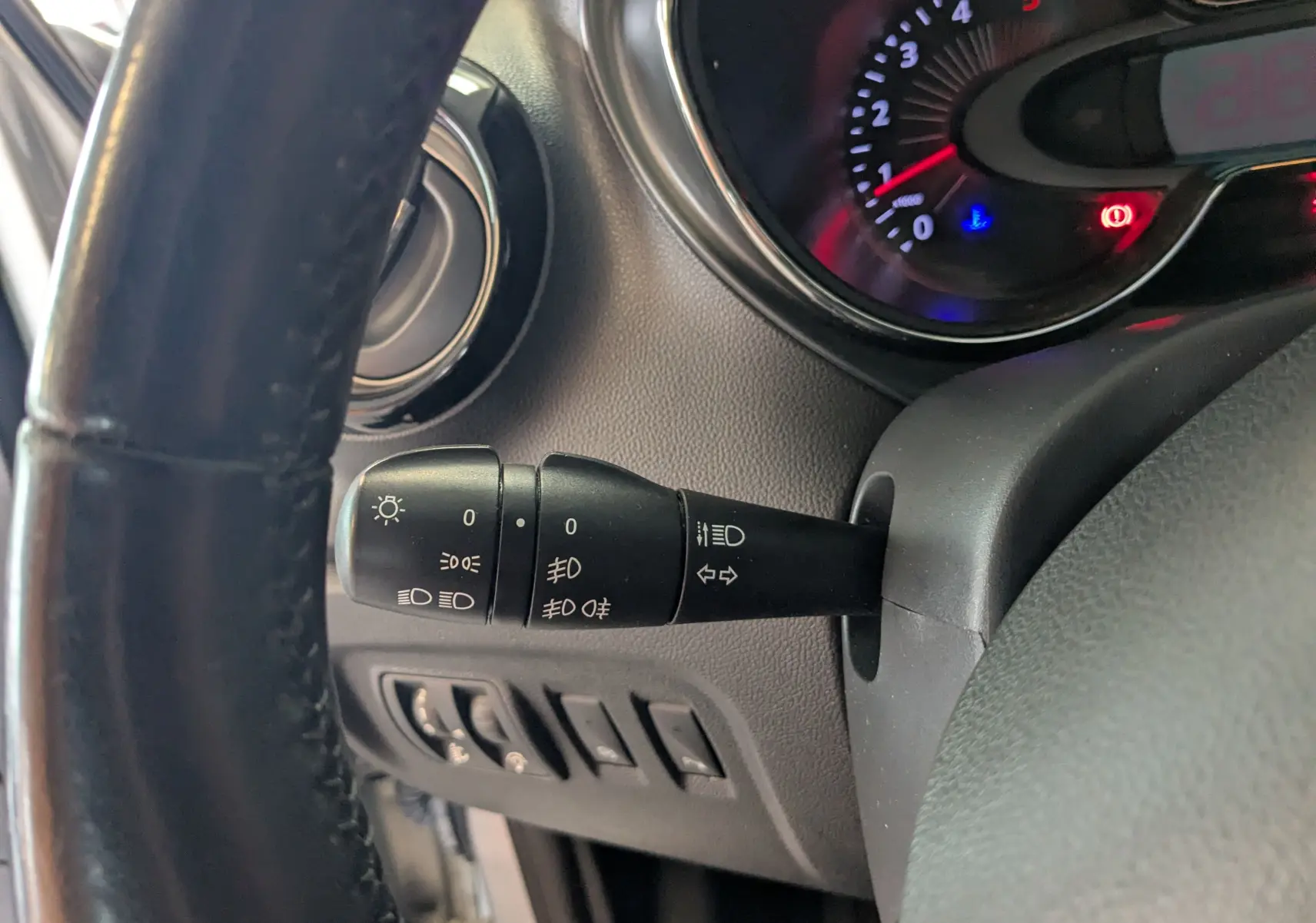 Gros plan sur la manette de commande des phares et clignotants côté gauche du tableau de bord du Renault Captur gris clair 2017.