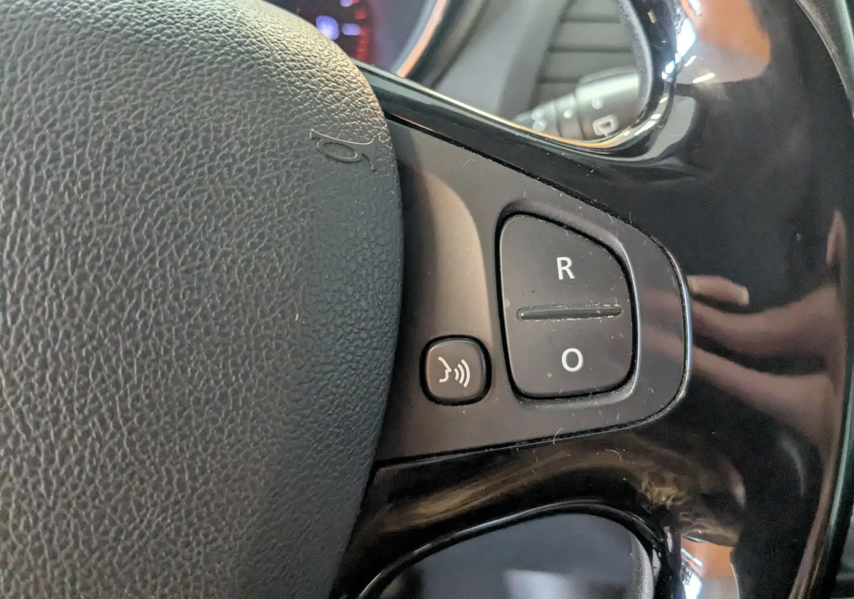 Gros plan sur les commandes vocales et de régulateur au volant noir du Renault Captur gris clair 2017, version 1.5 dci business.