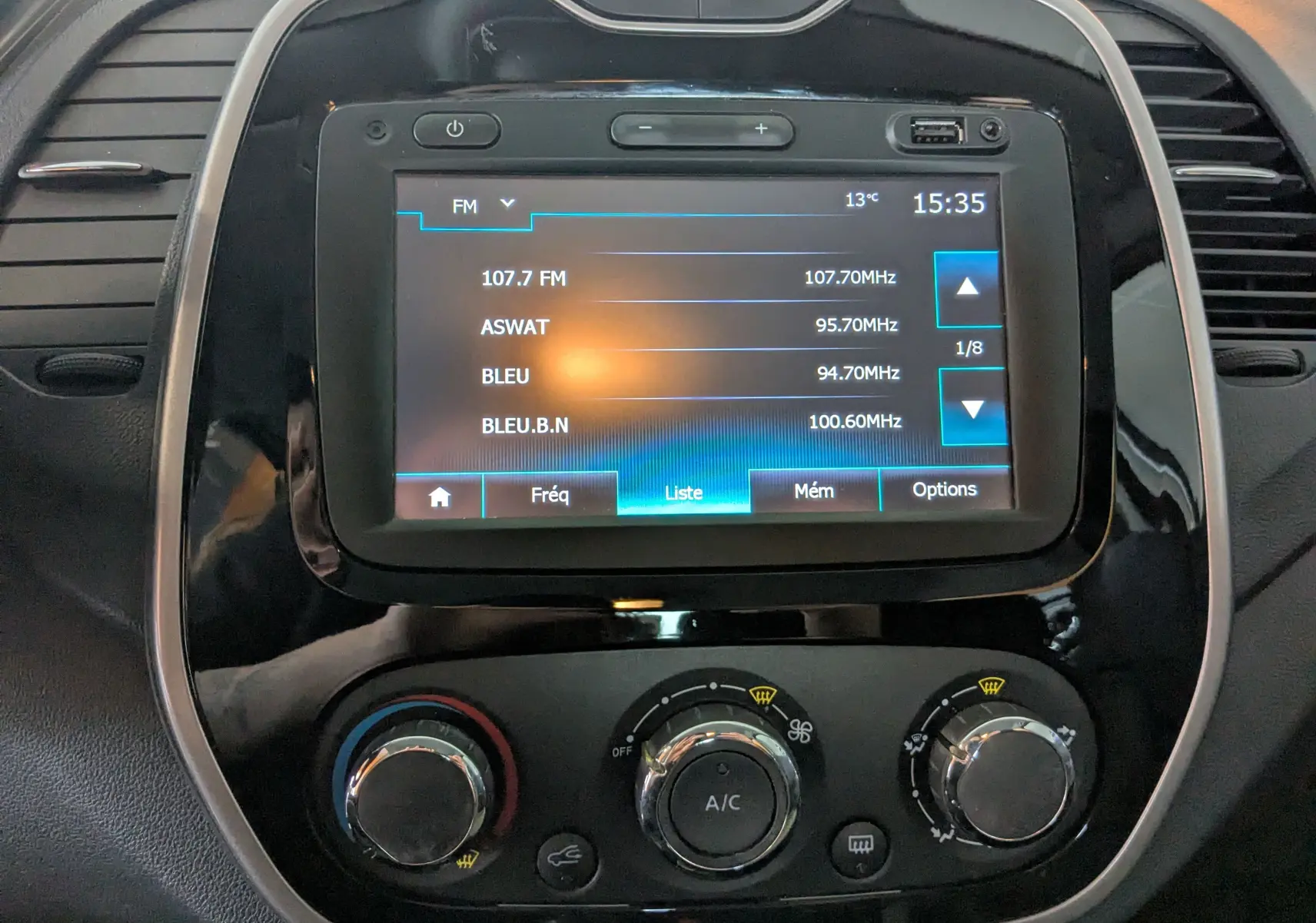 Vue rapprochée du tableau de bord du Renault Captur gris clair 2017, mettant en valeur l’écran tactile et les commandes de climatisation.