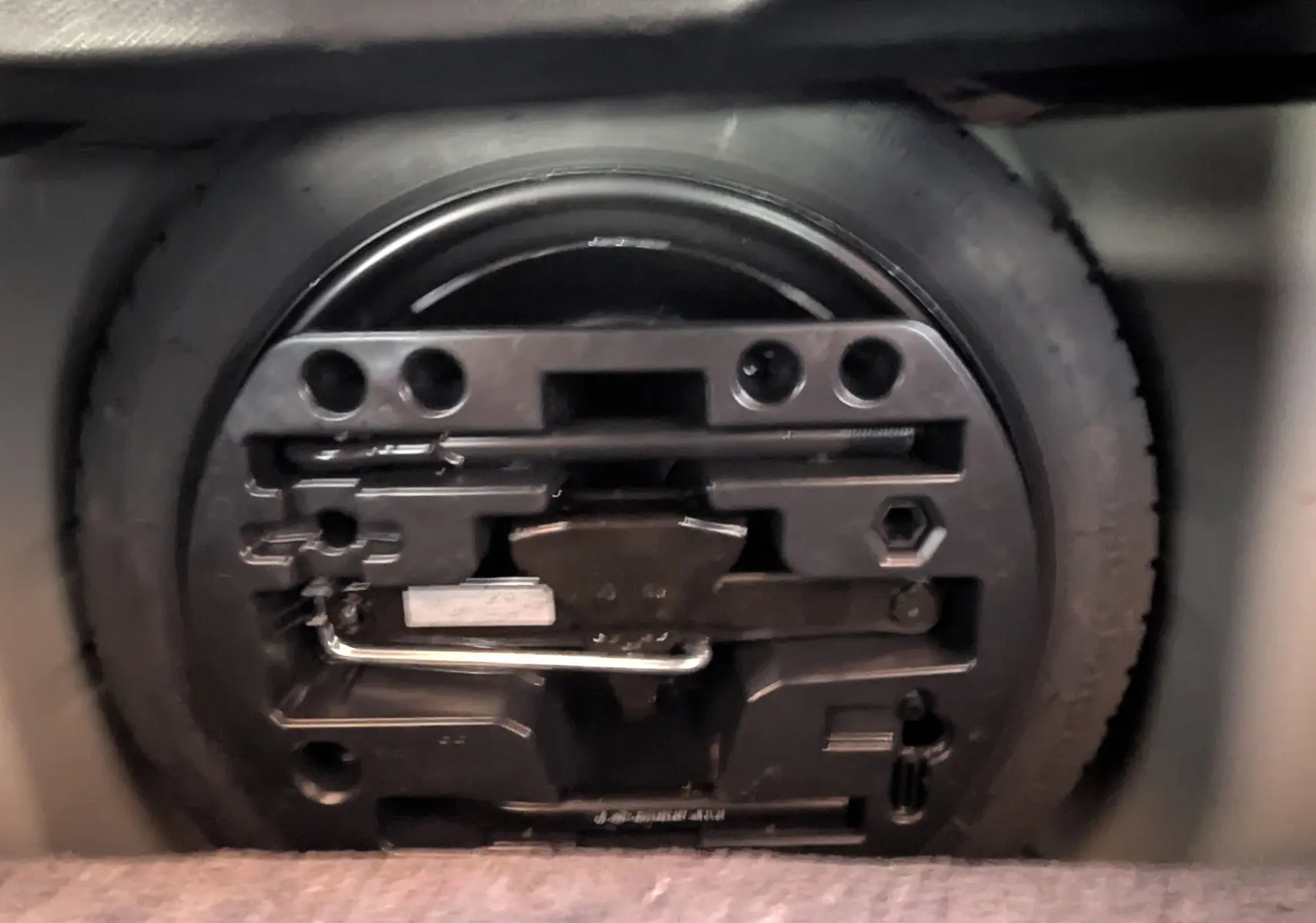 Gros plan sur la roue de secours et son kit d'outils rangés dans le coffre d'un Renault Captur gris clair 2017.