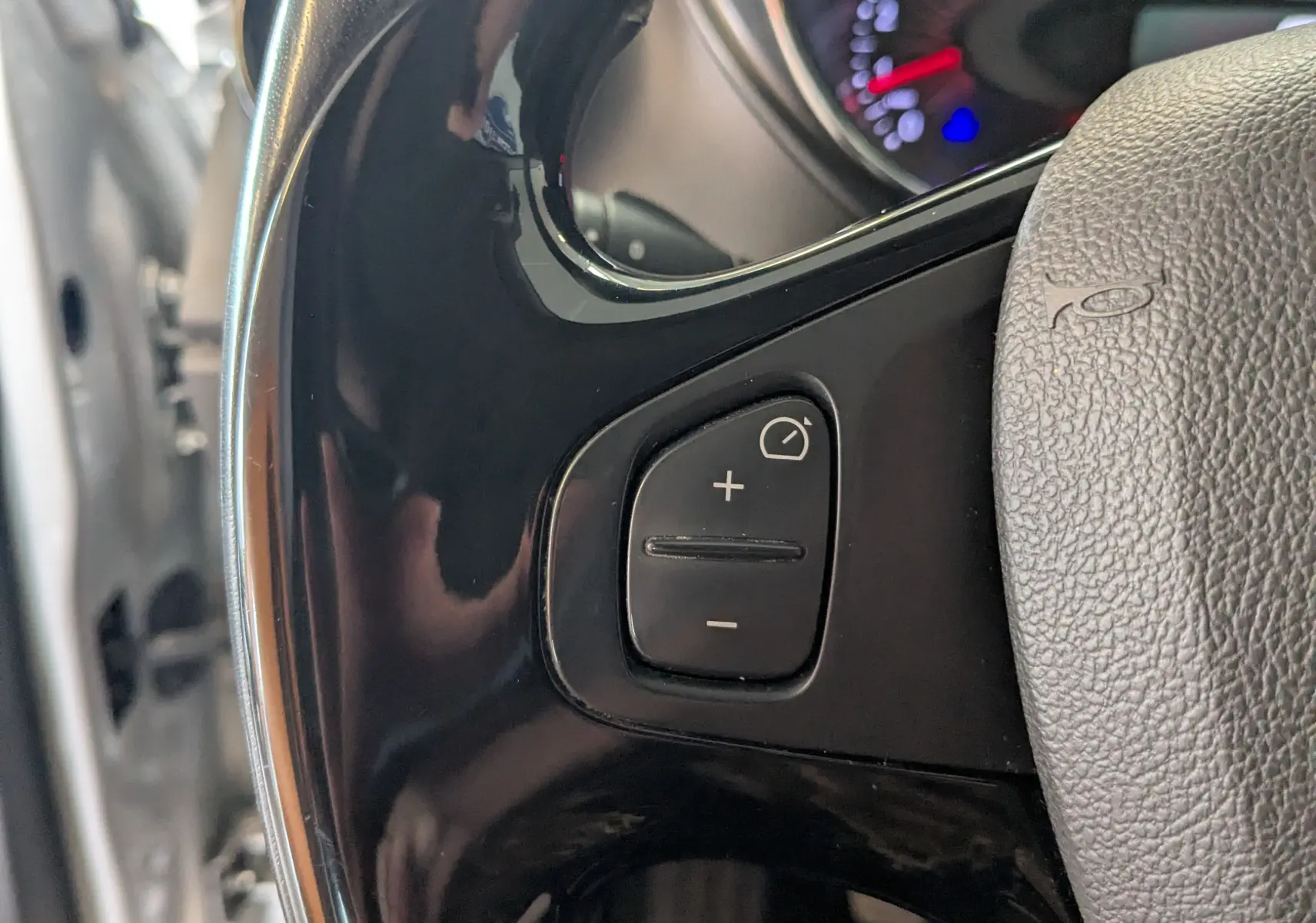Gros plan sur les commandes de régulateur de vitesse au volant d’un Renault Captur gris clair, intérieur noir.