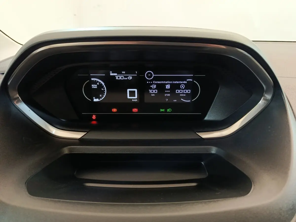 Tableau de bord numérique du Peugeot Partner 2025 affichant la consommation instantanée et les alertes, vue frontale rapprochée.