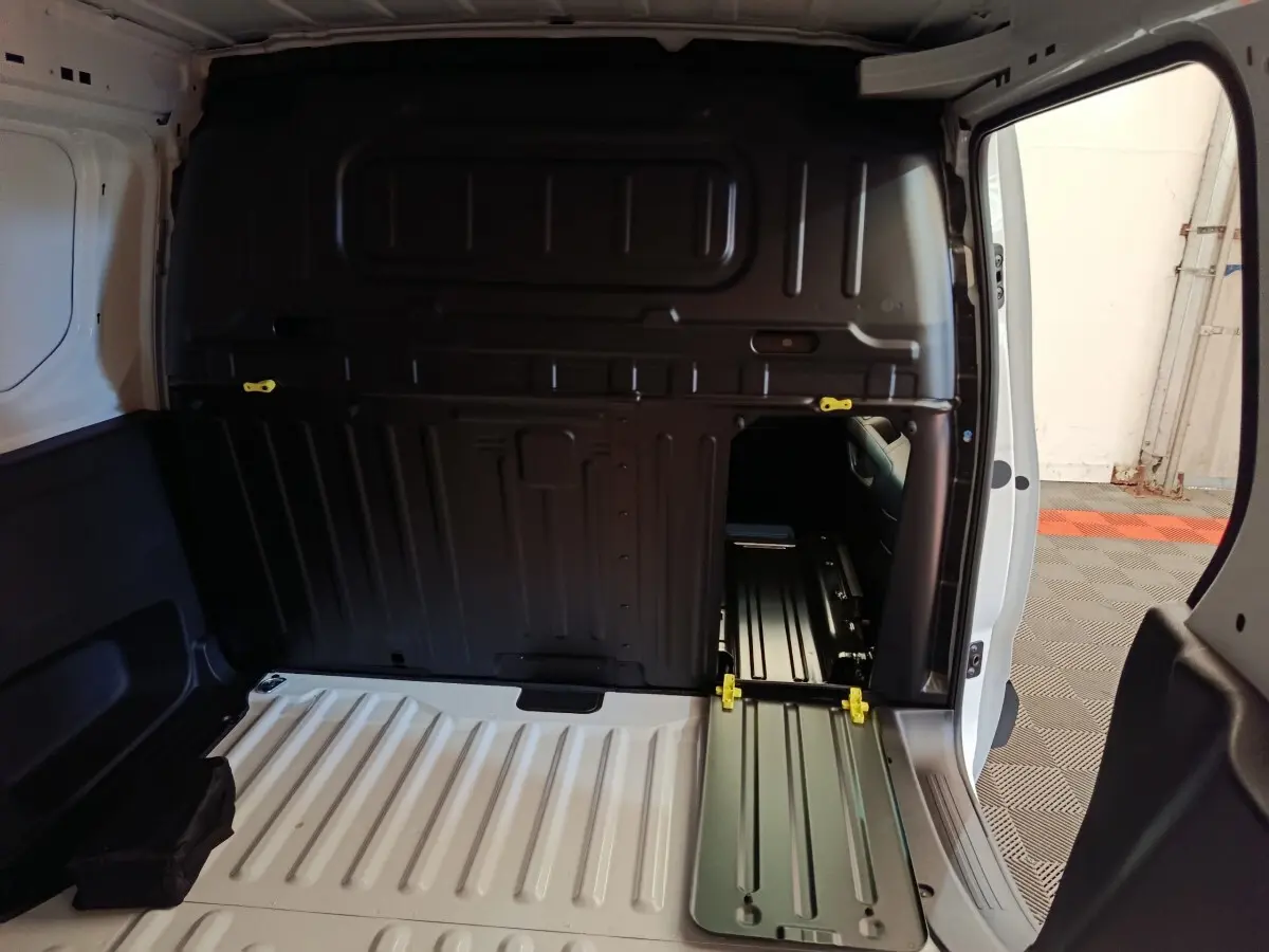Intérieur du coffre du Peugeot Partner blanc, vue arrière avec cloison pleine et trappe d’accès ouverte côté droit.