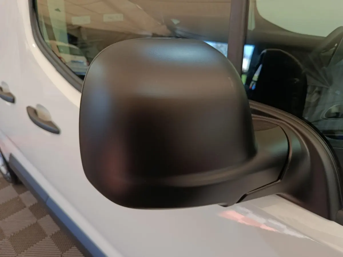 Gros plan sur le rétroviseur noir côté conducteur du Peugeot Partner blanc, avec vue partielle de la portière avant.